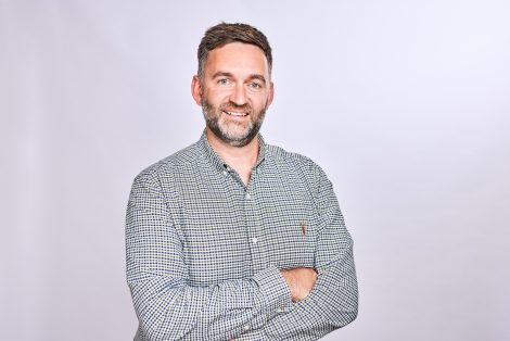 Tom Large of Land & New Homes Network smiling with arms folded, wearing a checked shirt